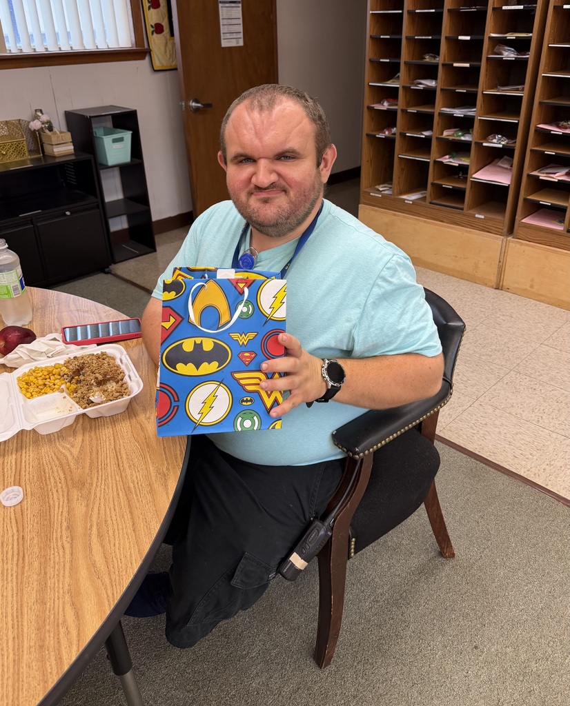 Mr. Herny in a light blue shirt holding a gift bag.