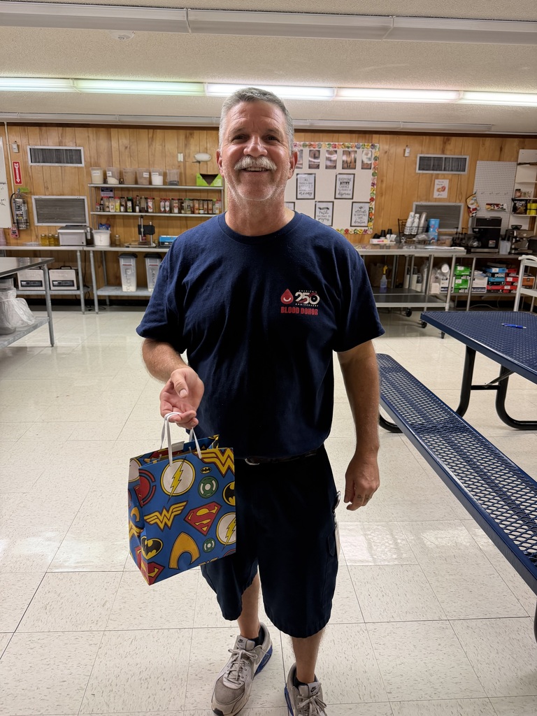 Mr. David male custodian in blue pants and a blue shirt holding a gift bag.