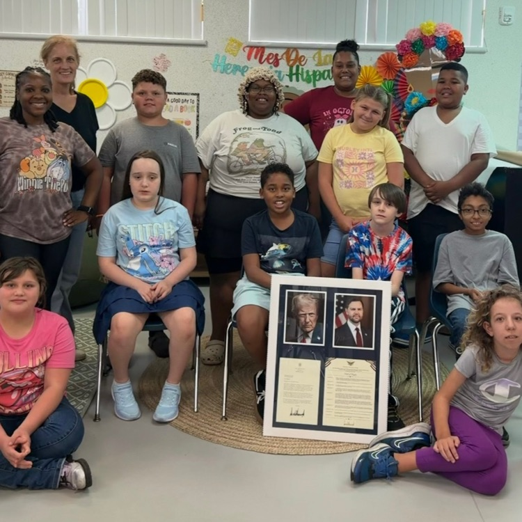 class pose for a picture with a framed letter from the White House  