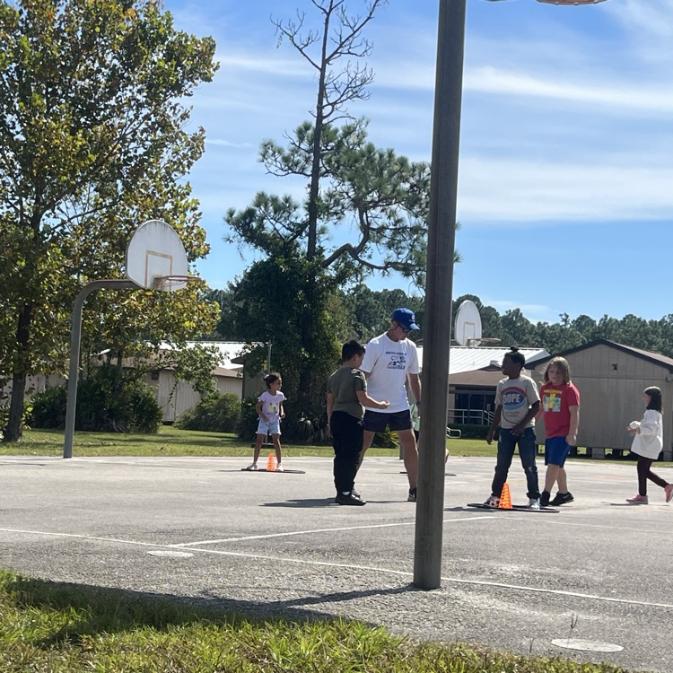 PE coach standing with students around a cone