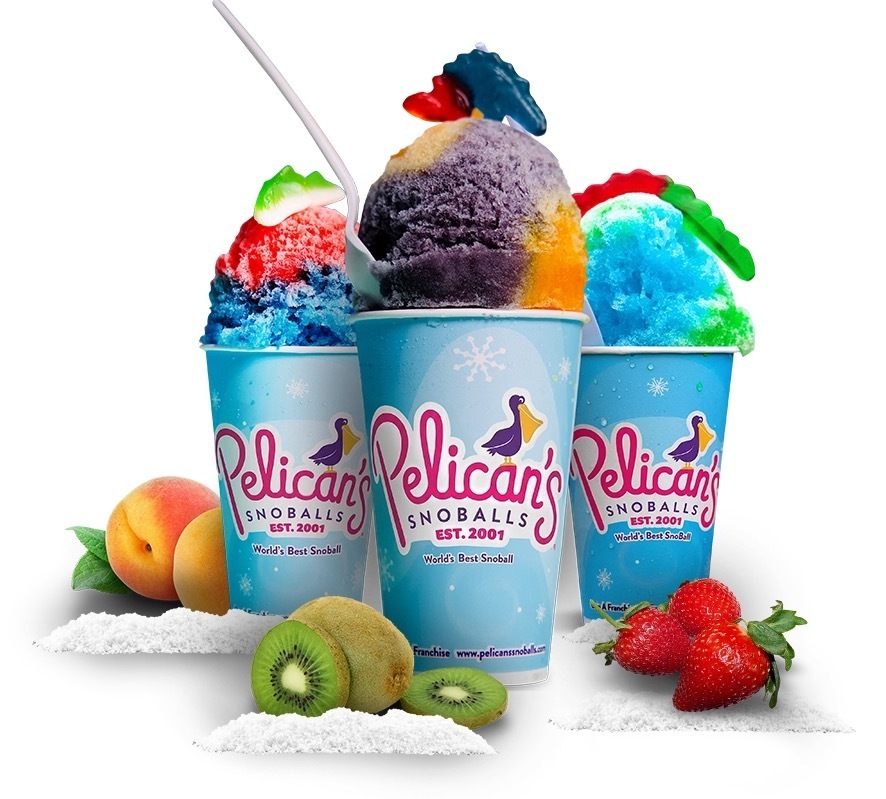 Three cups of snow cones with fruit toppings and straws. Cups have Pelican's logo. Surrounding fruits include strawberries, peaches, kiwis, and sugar.