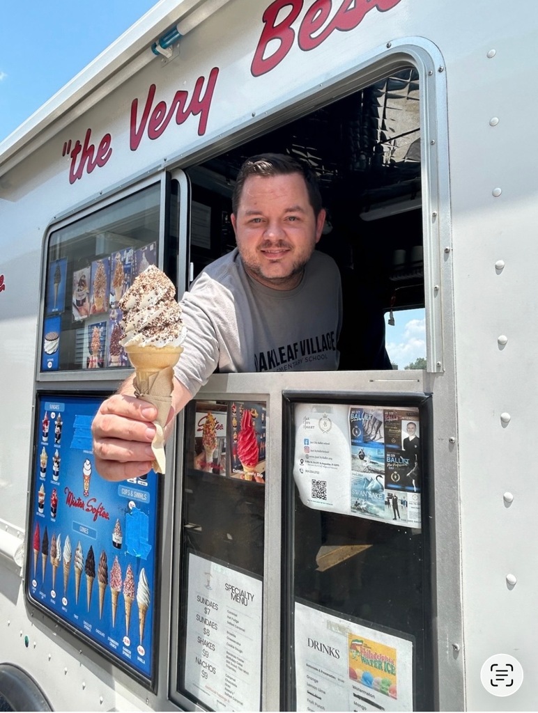 Mr. Martin holds a cone of ice cream outside an ice cream truck with a menu and advertisements on its side.