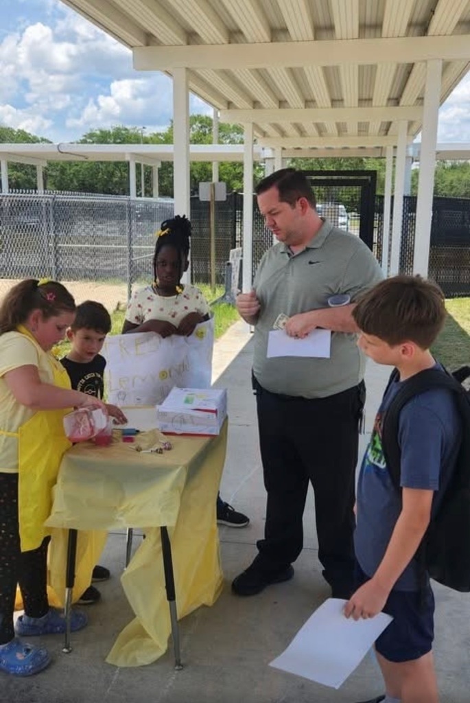 Mr. Martin and children gather ata lemonade stand.