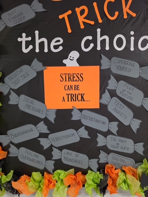 A bulletin board with "TRICK the choice" in white letters. Below it, orange and grey candy-like shapes with phrases. An orange label reads "Stress can be a trick."