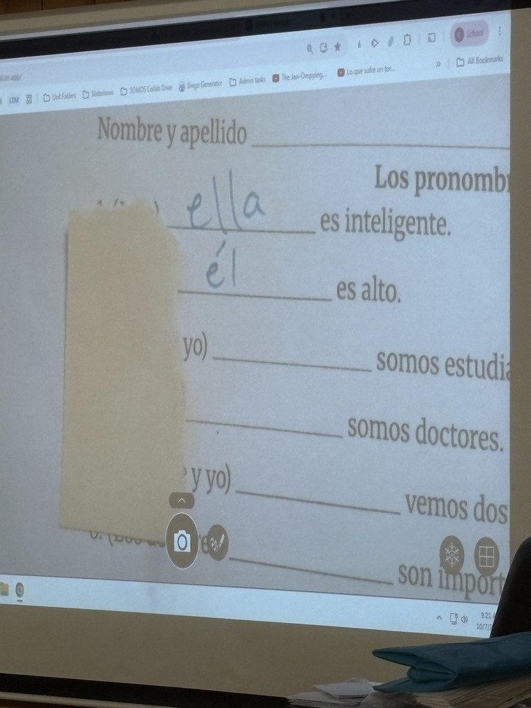 A classroom presentation screen displays a Spanish lesson about pronouns. The lesson includes words such as "Nombre y apellido" and "es inteligente."