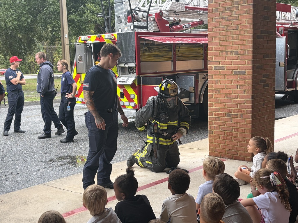 Students watch a firefighter demonstrate his gear