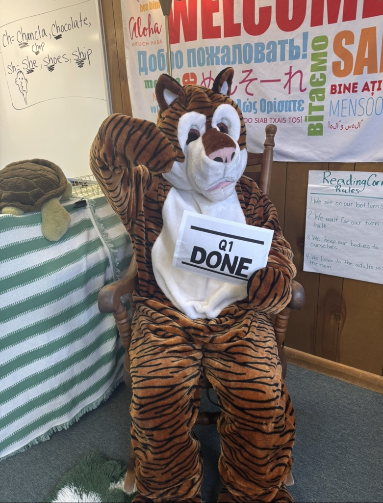 A tiger sitting in a chair and holding a sign that says Q1 Done