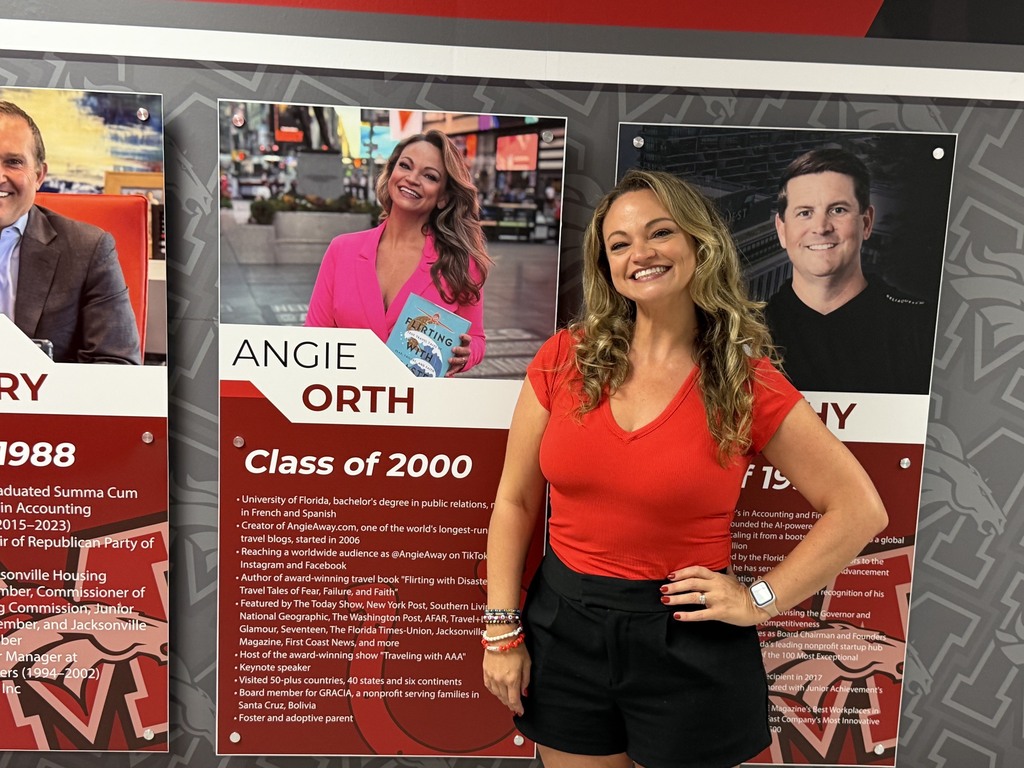 A woman stands in front of a wall with three posters behind her, all with people in various poses and the words "Class of 2000" on the middle poster.