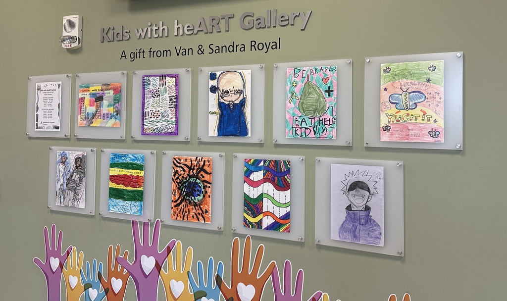 Artworks in colored frames hang on a wall. Below, painted hands with hearts surround the frames.