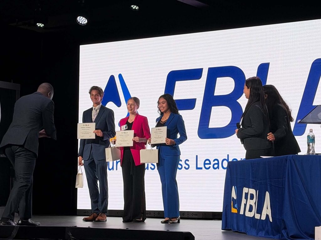 People on stage, receiving awards. A blue table with an FBI logo is in the background.