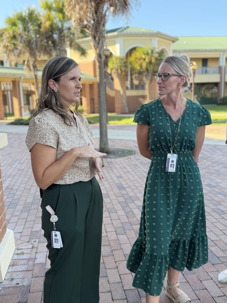 Two female assistant principals talking about their school in the courtyard area of the school.