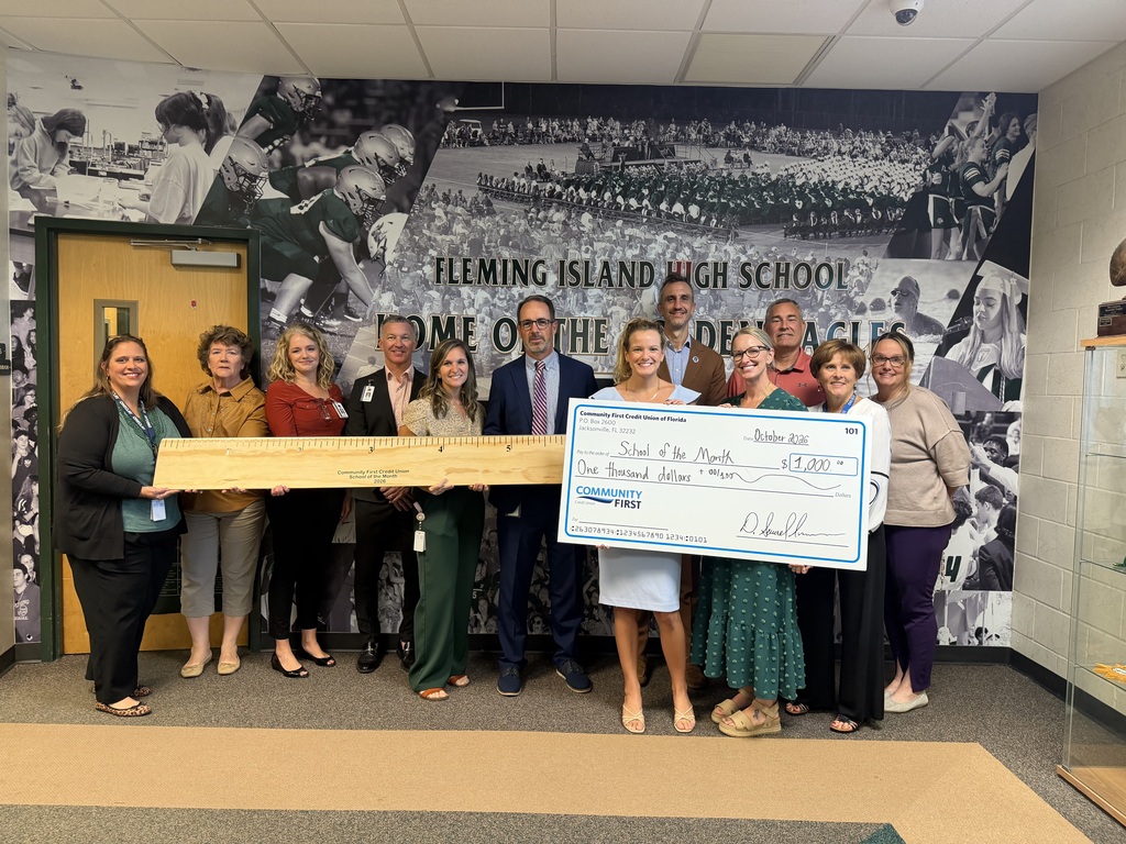 A group of individuals from Fleming Island High who are holding a check and a large sized ruler from community first credit union