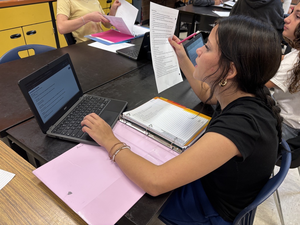 student working in a textbook and chromebook