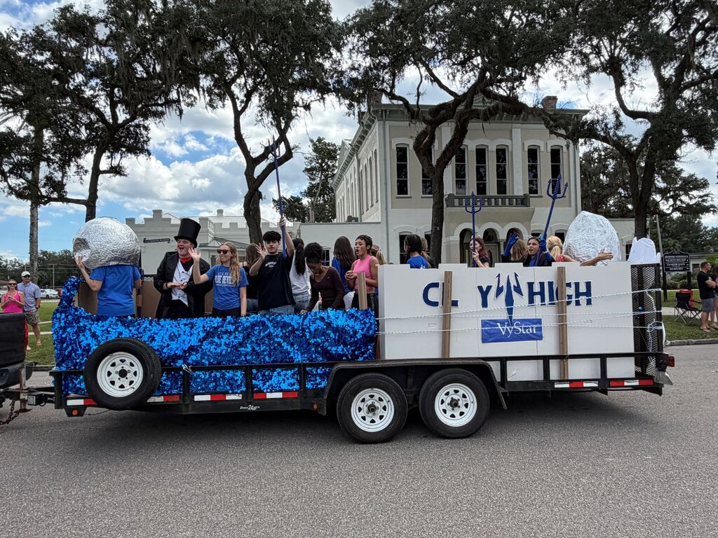 Parade float with people in hats and tops with text "CY HIGH" on the side.