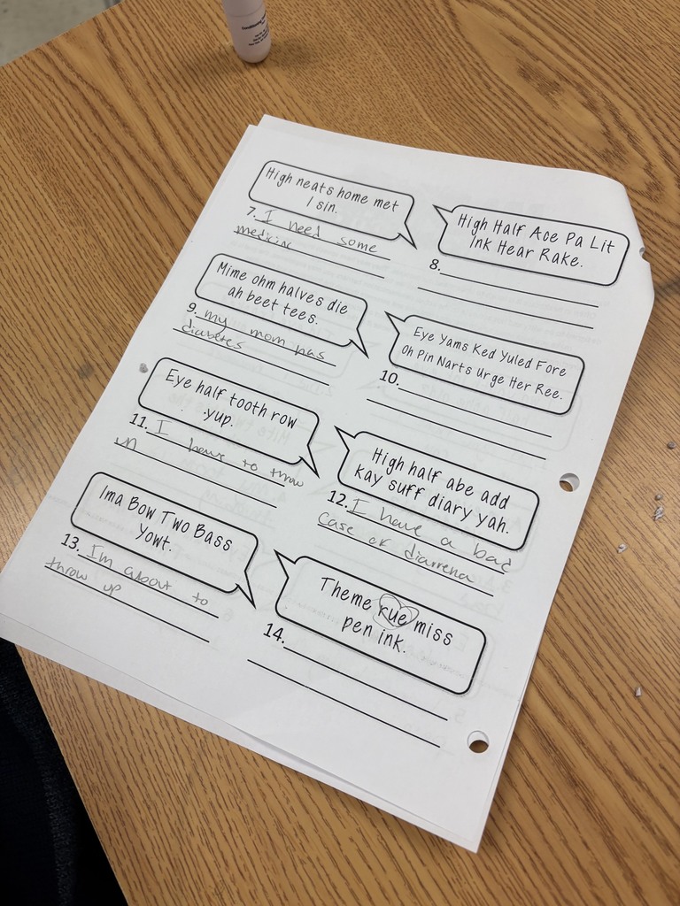 A worksheet with text and speech bubbles placed on a wooden table. Text includes a theme and numbers.