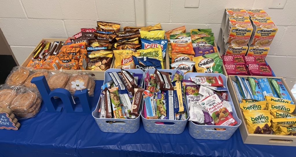Table with various snacks in bins, including chips, cookies, and bread, on a blue cloth.