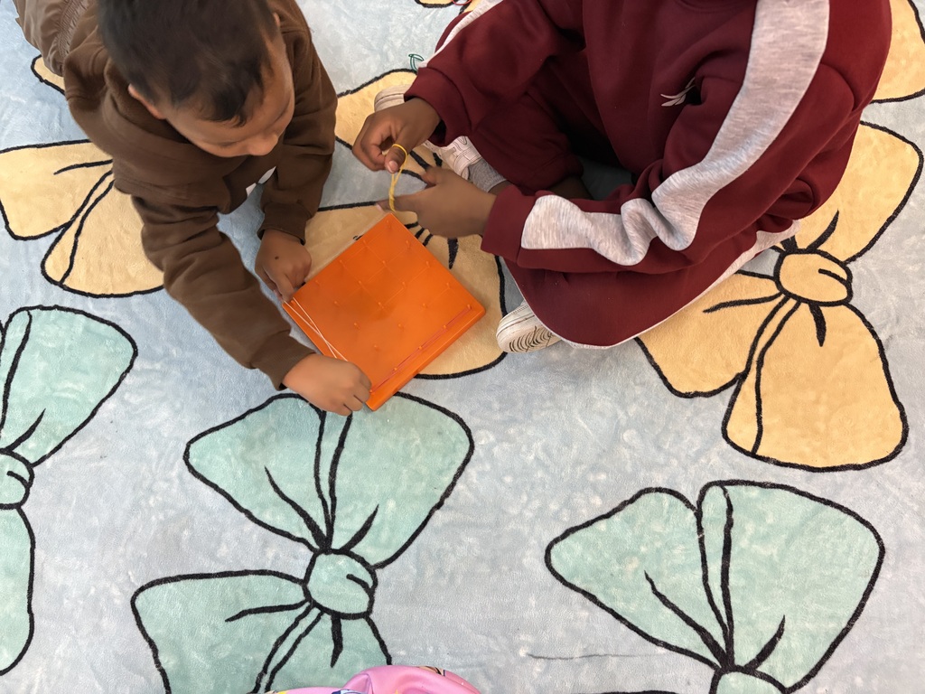 Students use rubber bands to build shapes on geoboards.