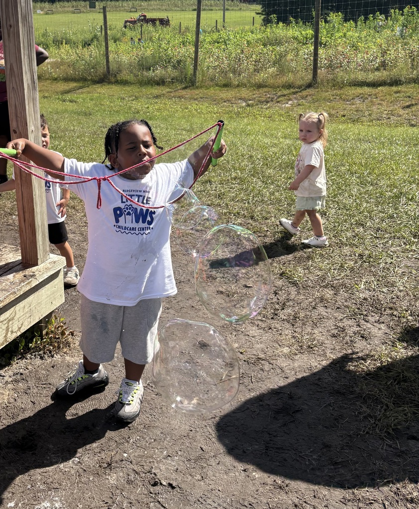 Two little kids playing outdoors with bubbles.