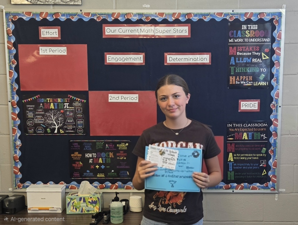 Person holding certificate stands in front of bulletin board with red, black, and white squares.