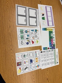 Several sheets of paper with colorful pictures and text arranged on a brown wooden table.