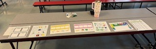 Desk with various colorful papers and a white cup. Behind it, two red benches on a gray floor.