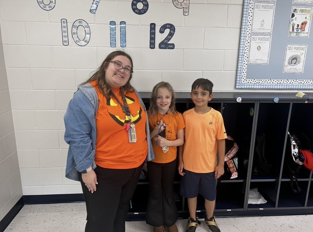 An adult woman and two children stand near lockers, with numbers 10, 11, and 12 on a white wall.