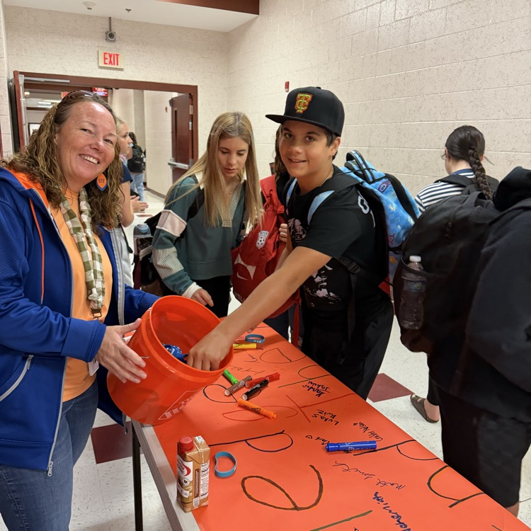 A picture of a teacher and student signing a pledge to end the R word