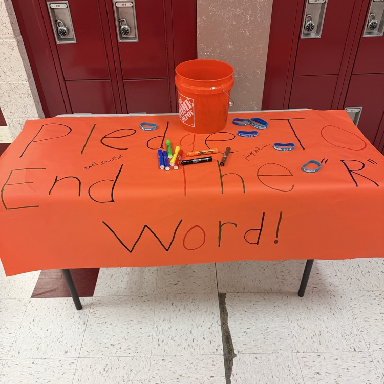 A picture of a teacher and student signing a pledge to end the R word