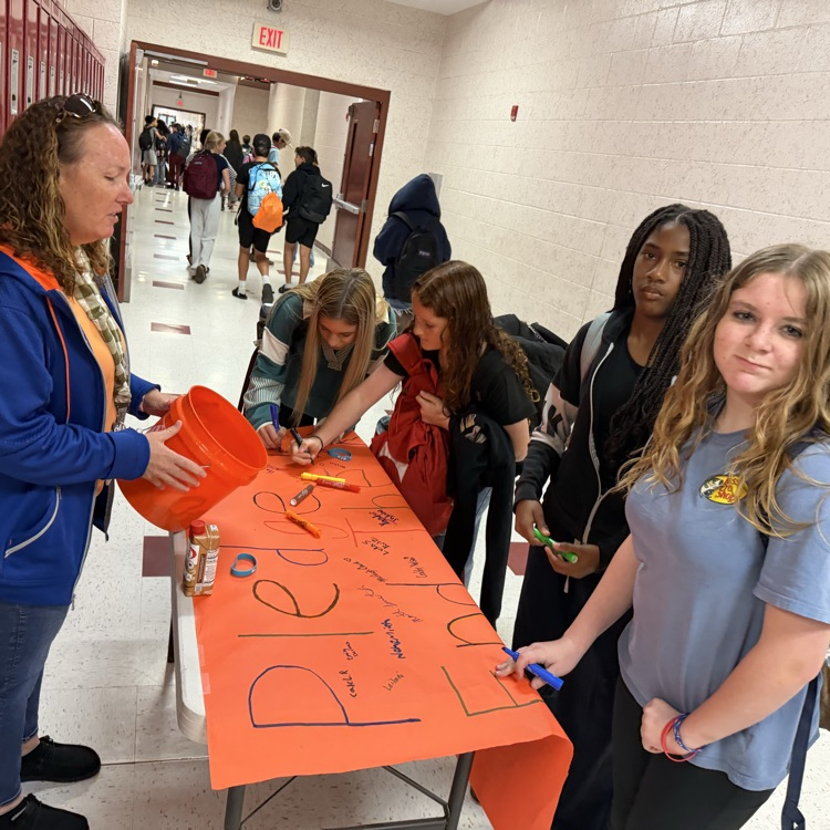 A picture of a teacher and student signing a pledge to end the R word