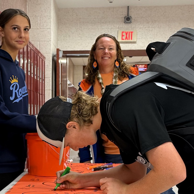 A picture of a teacher and student signing a pledge to end the R word
