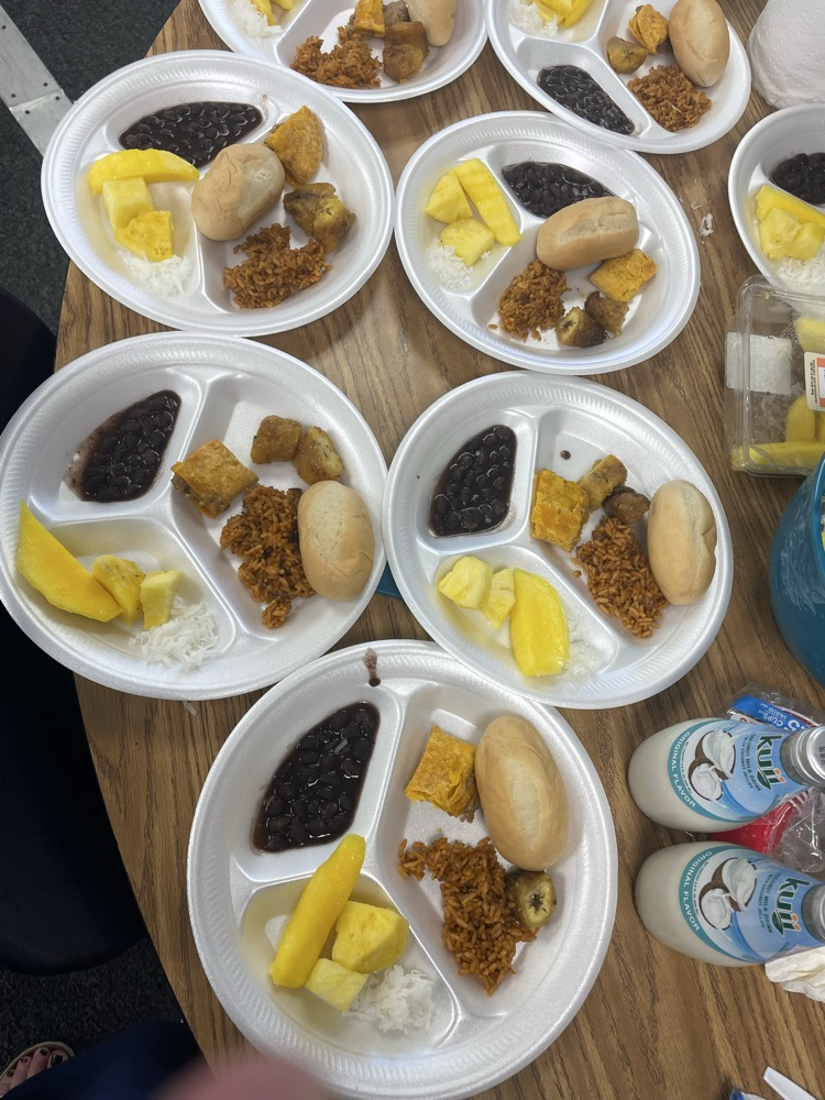 Several white plates filled with various food items. Food includes rice, beans, yellow fruit, and bread.