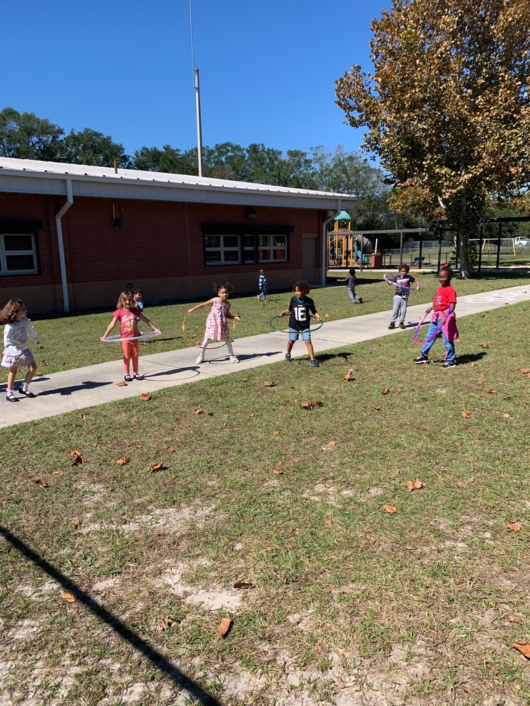A group of children are walking on a sidewalk at a school, with some holding ropes.