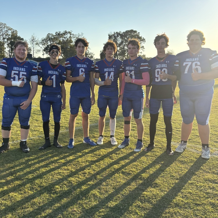 Six football players in blue uniforms standing on a field with numbers 55, 1, 6, 14, 93, and 76.