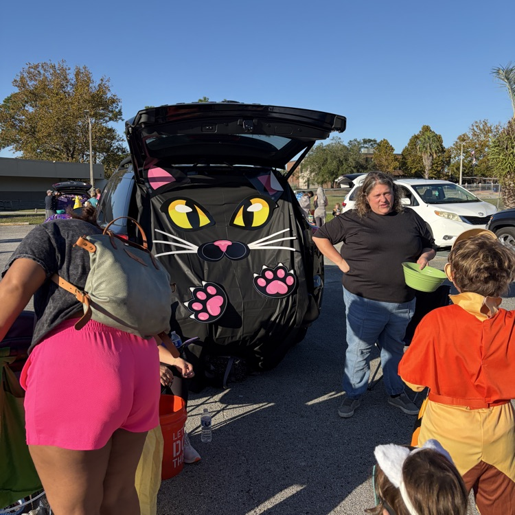 Group of children in costumes with a decorated car with cat ears and a trunk opening.