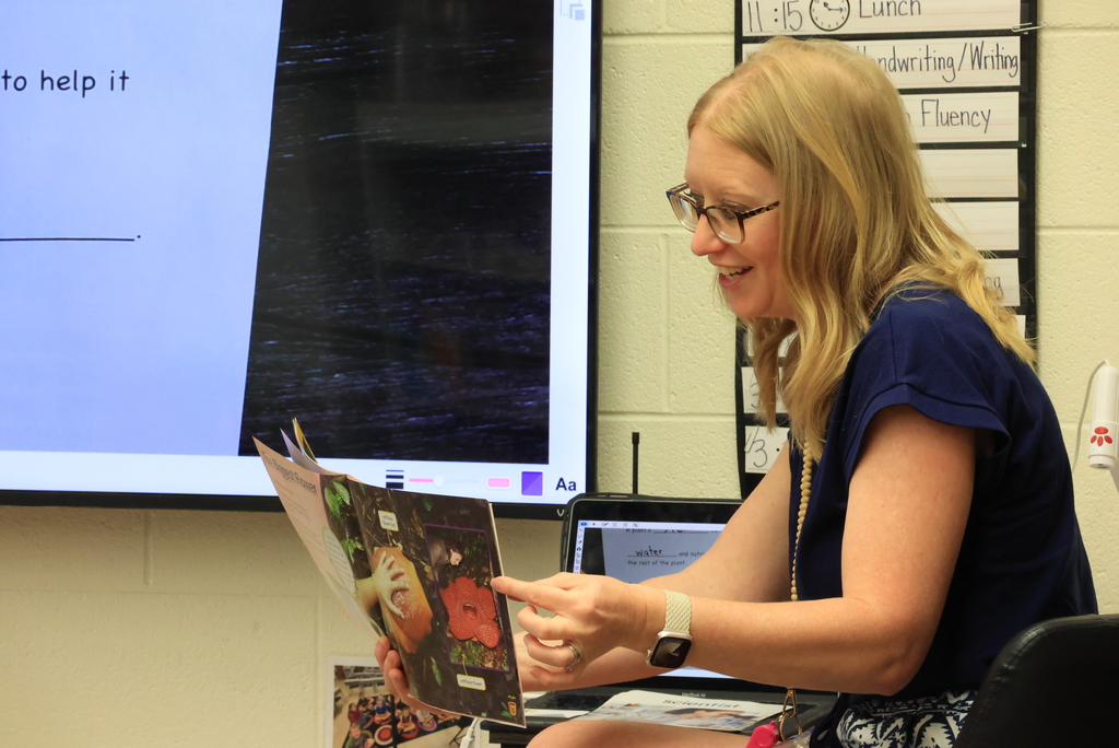Mrs. Lange reads a book to her students and helps them take notes.