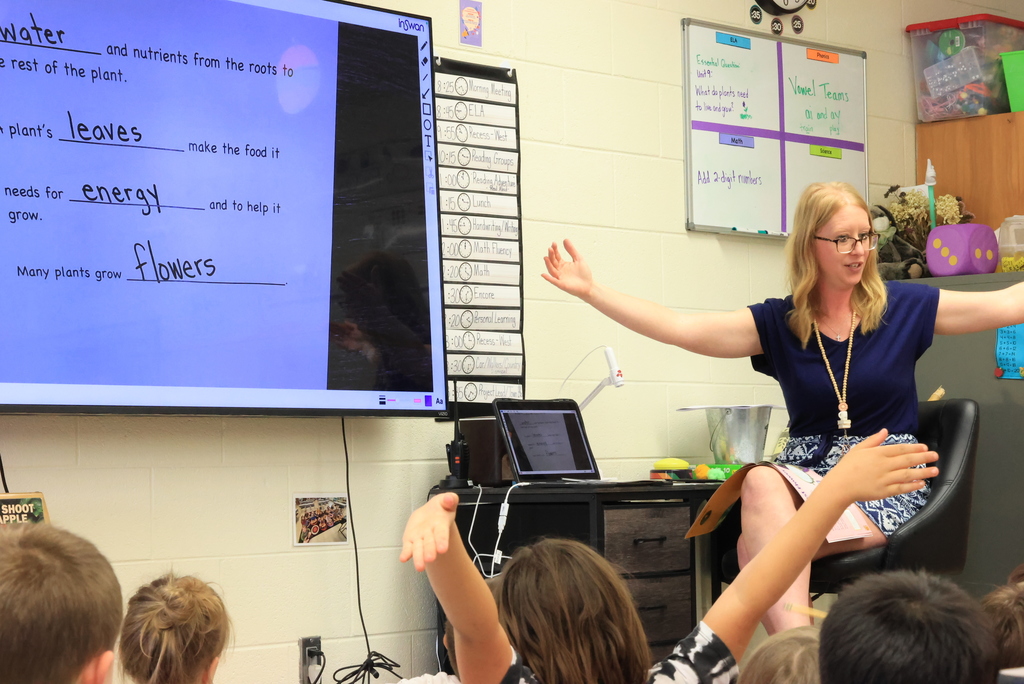 Mrs. Lange reads a book to her students and helps them take notes.