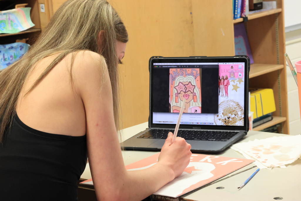 A student uses a computer graphic to help her draw her self portrait.