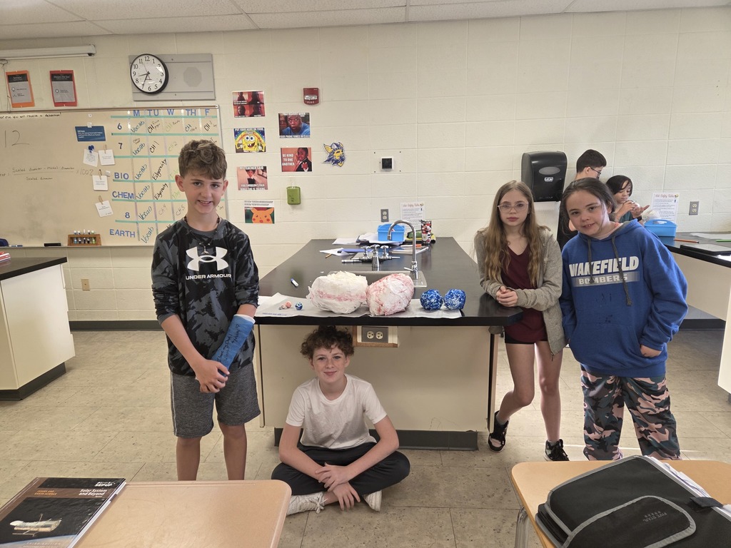 6th grade students in Mrs. Trembath’s science class display handmade scale models of the planets, created using materials like Styrofoam, tin foil, and toilet paper, as part of a solar system project that also incorporated math skills and percent error calculations.