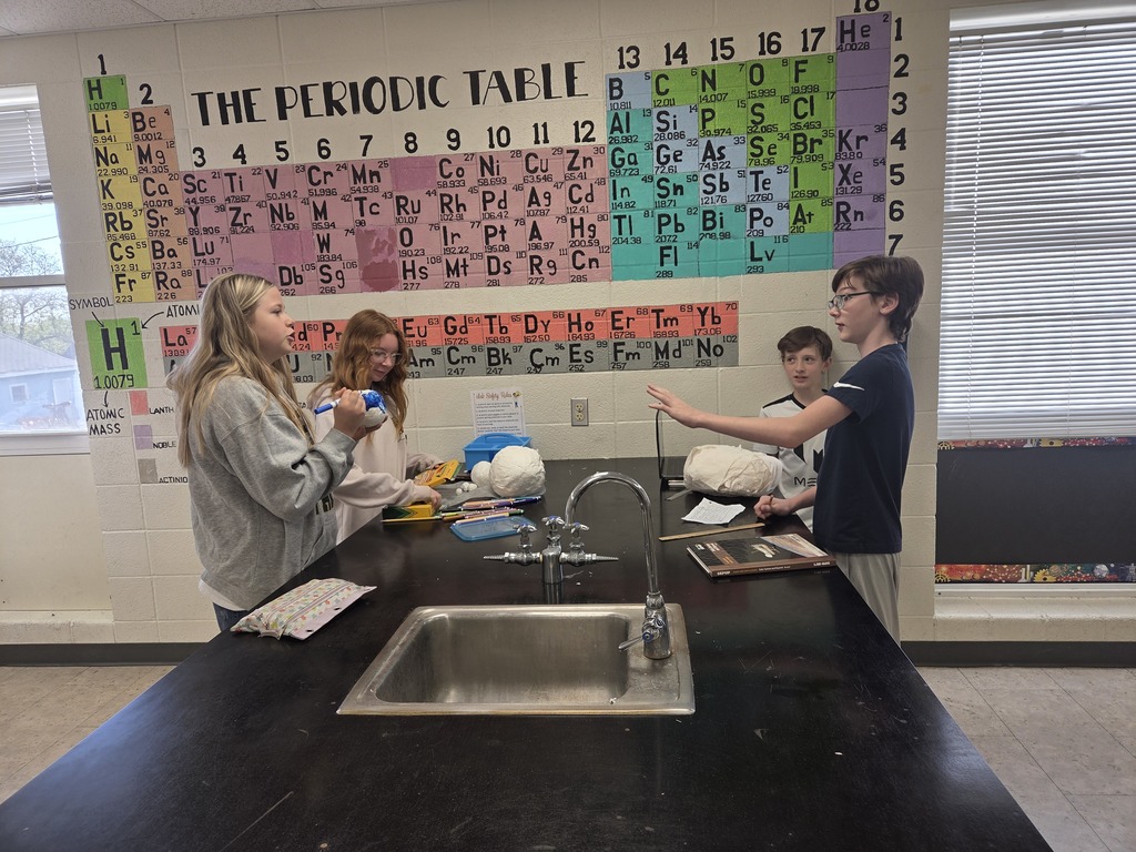 6th grade students in Mrs. Trembath’s science class display handmade scale models of the planets, created using materials like Styrofoam, tin foil, and toilet paper, as part of a solar system project that also incorporated math skills and percent error calculations.