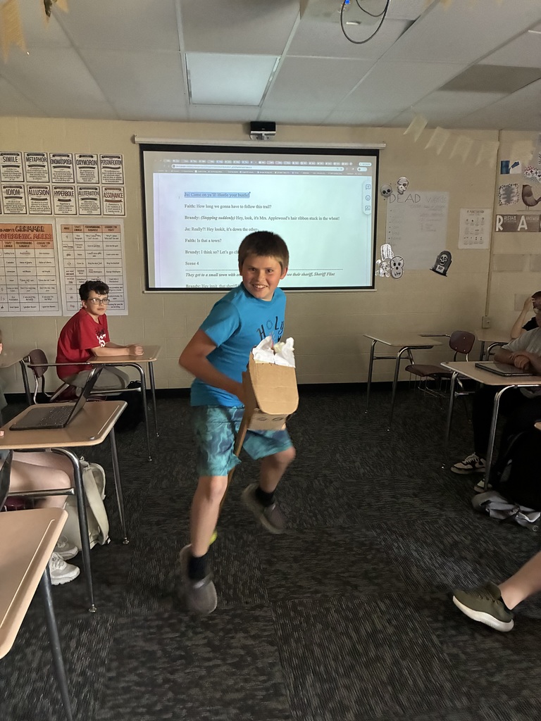 A student rides a pretend horse as part of the play that the class wrote together.