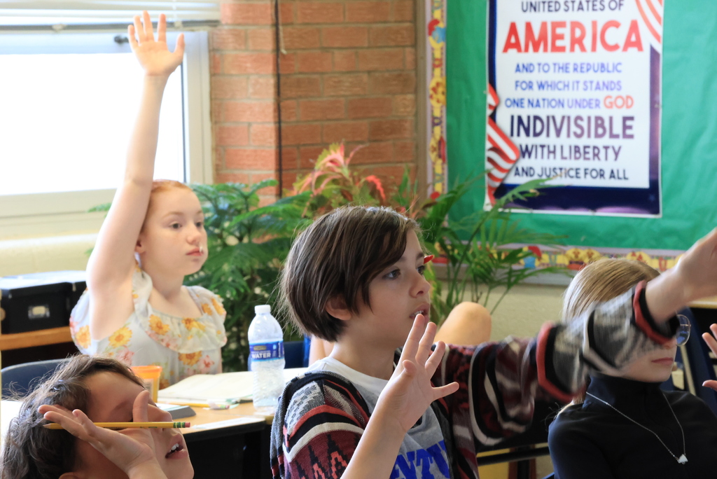 Students raise their hands to answer questions during math class.