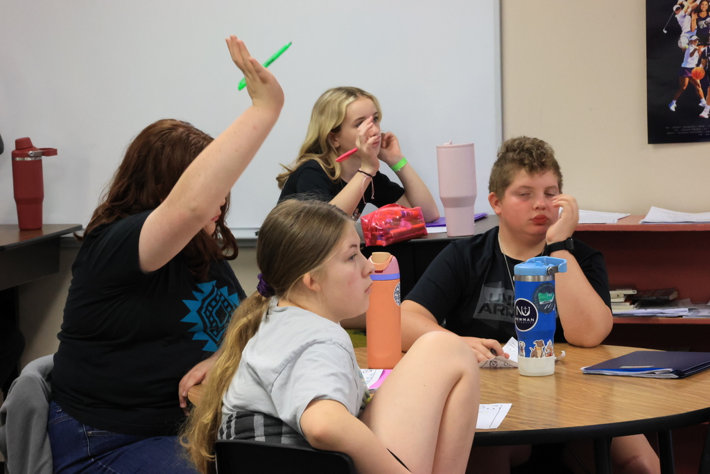 A group of students raise their hands to answer review questions in Mrs. Griffiths' math class.