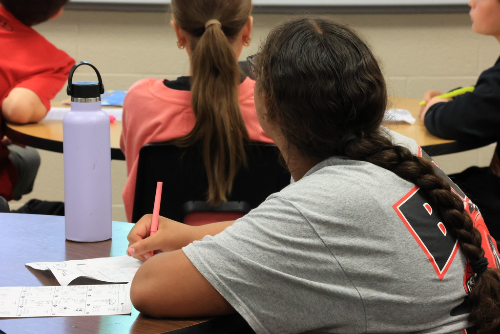 A group of students write down answers to review questions in Mrs. Griffiths' math class.