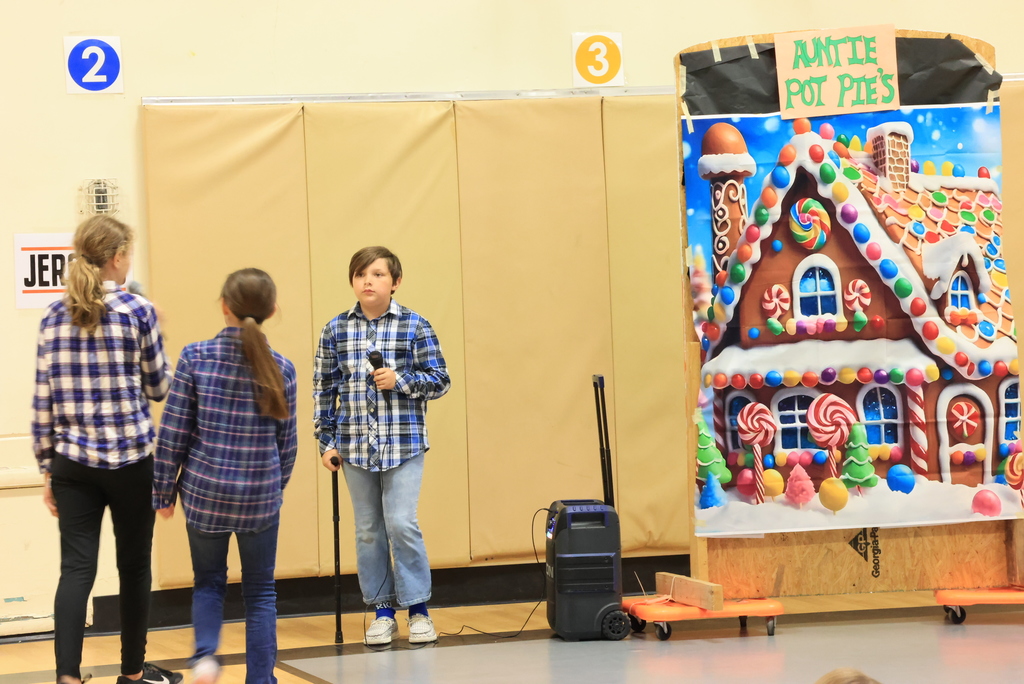 Students speak into the microphone and act out a scene during the play, 'Blame it on the Wolf."