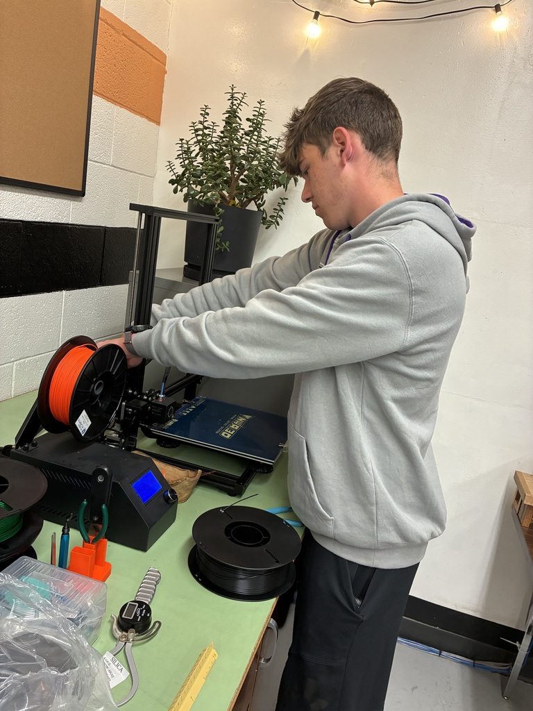 Seniors Caden Peterson works on the 3-D printer getting it ready to print their bridge.