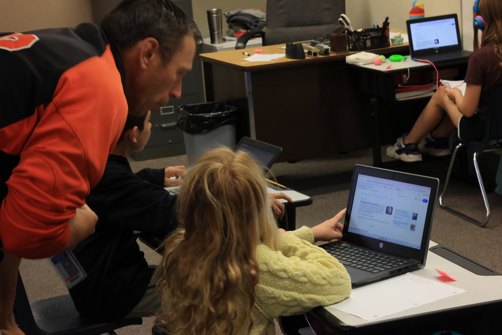 Mr. Bent looks over a student's shoulder looking at their planetary data that is on their laptop.