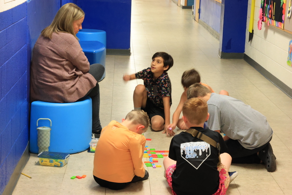 Students play a domino work prefix game in the hallway.