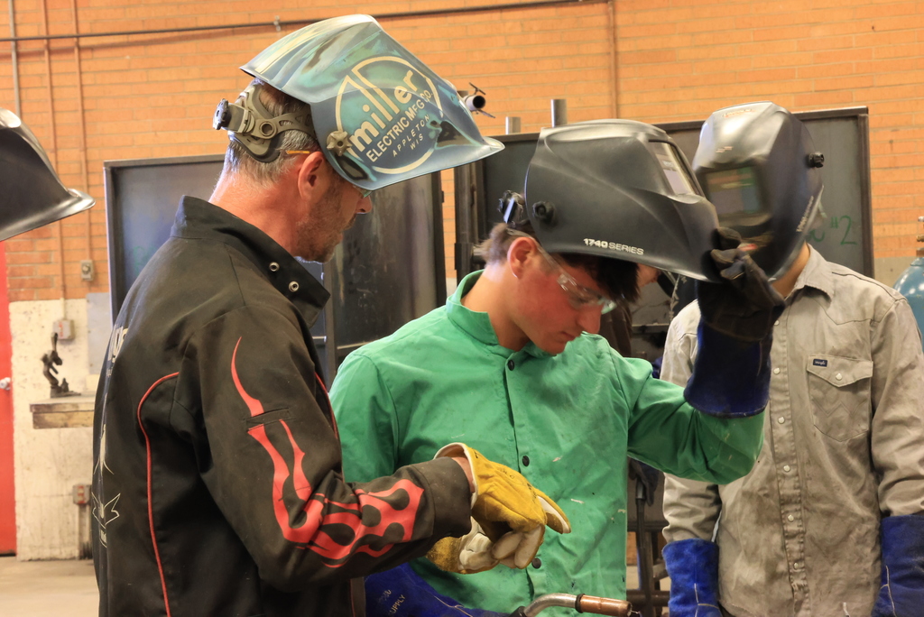 Double L Manufacturing owner Thomas Milligan talks with a student about his welding patterns.