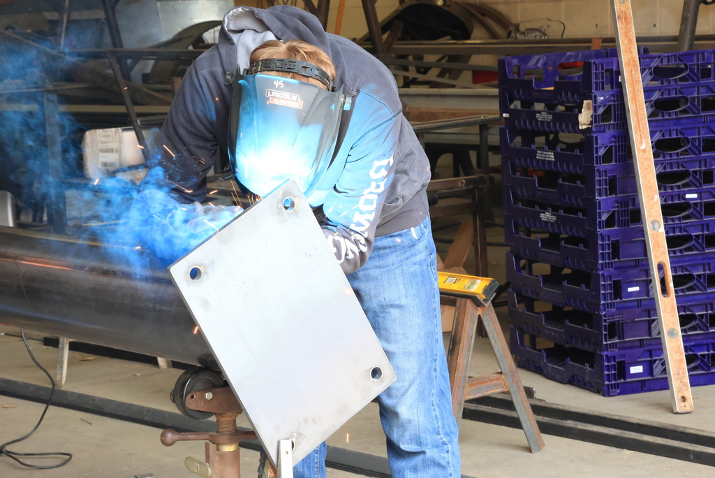 A student welds part of the billboard into place.