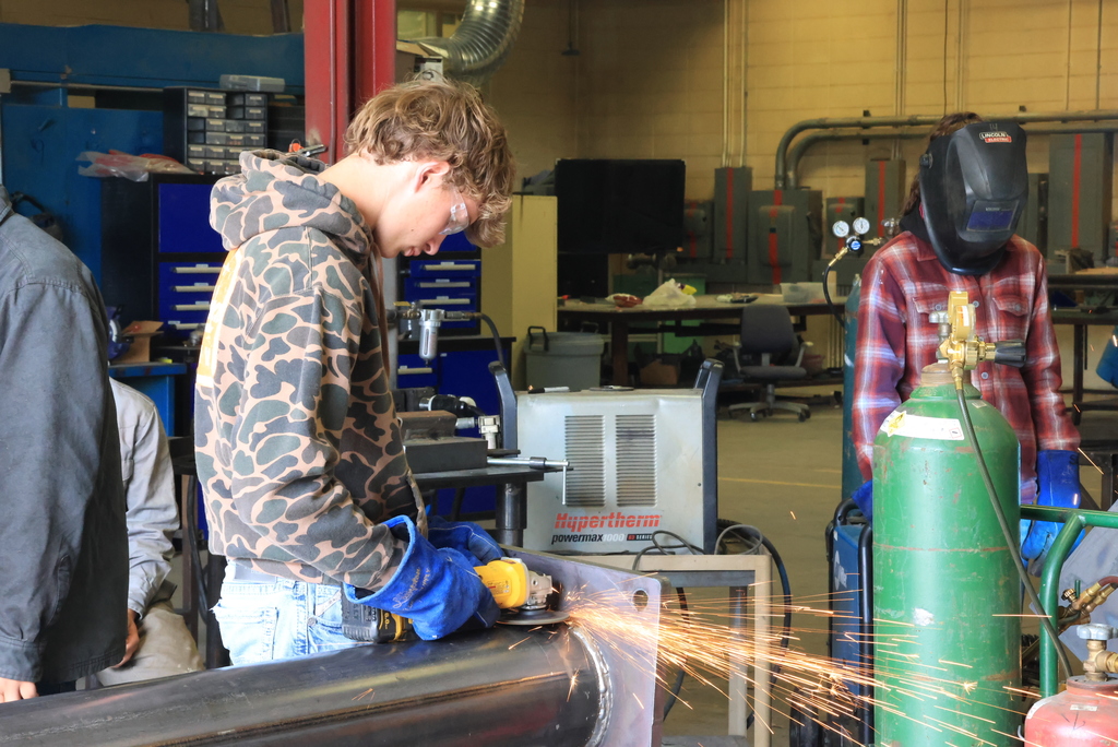 A student grinds the finished weld on the billboard stand.